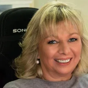 Eine lächelnde Frau sitzt in einem schwarzen Stuhl.