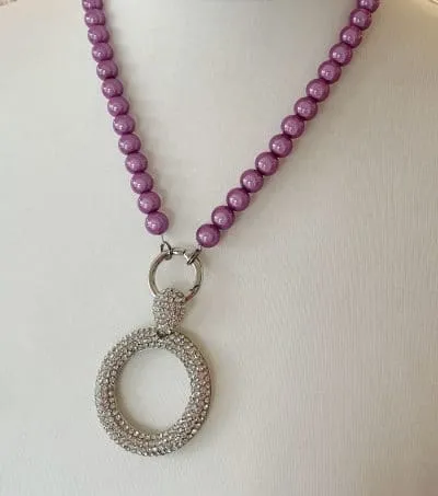 Erlebe den Wow-Effekt mit dem Round Crystall Wechselanhänger! Stell dir vor, wie dieses elegante Schmuckstück an deinem Hals funkelt – inszeniert auf einer weißen Mannequin-Büste könnte es nicht besser zur Geltung kommen. Die lila Perlenkette mit goldfarbenem Verschluss und funkelnden Strasssteinen sorgt für das ultimative Style-Upgrade. Perfekt abgerundet durch eine einzelne, runde Perle zieht sie alle Blicke auf sich. Mach dich bereit für deinen strahlenden Auftritt!.