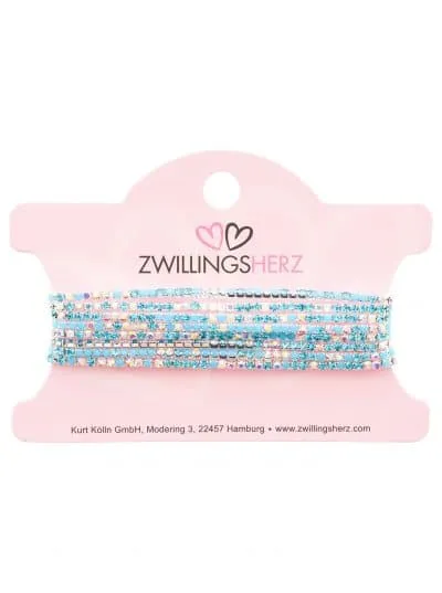 Ein Set Armbänder mit kleinen blauen und rosa Perlen, akzentuiert durch Glitzer. Auf der Verpackung steht „Zwillingsherz“ in Schwarz neben einem rosa Herz-Logo, wodurch der Produktname „More Glitzer“ hervorgehoben wird.