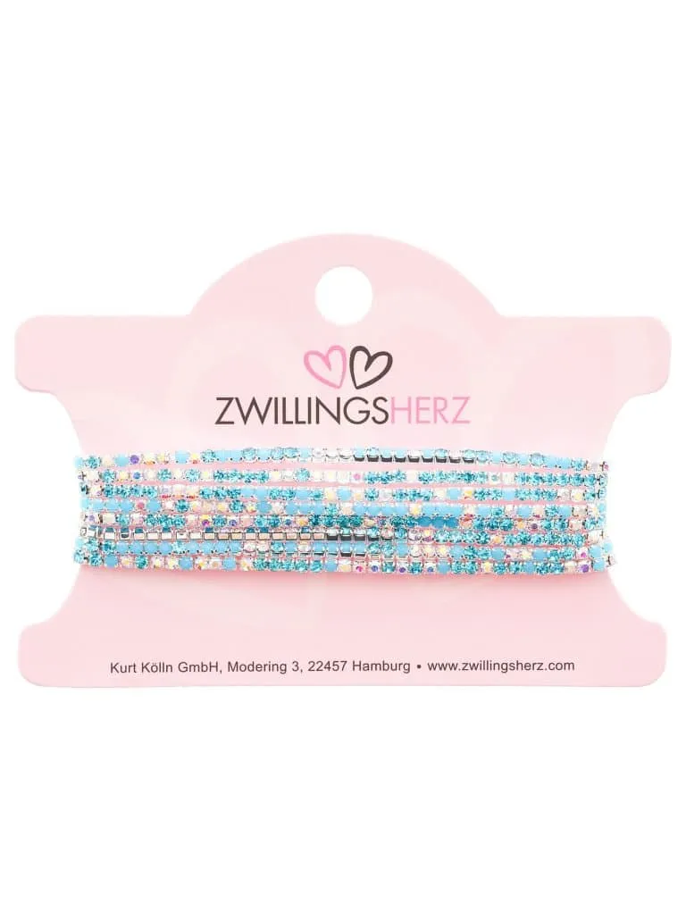 Ein Set Armbänder mit kleinen blauen und rosa Perlen, akzentuiert durch Glitzer. Auf der Verpackung steht „Zwillingsherz“ in Schwarz neben einem rosa Herz-Logo, wodurch der Produktname „More Glitzer“ hervorgehoben wird.