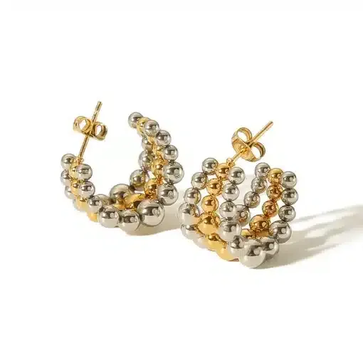 Ein Paar Creolen mit abwechselnd goldenen und silbernen Metallperlen. Die Ohrringe sind mit einem Ohrstecker versehen und dreidimensional und geschichtet auf weißem Hintergrund angeordnet.