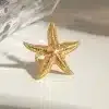 Entdecken Sie den Zauber des Beach Star Rings! Stell dir vor, du trägst diesen goldfarbenen, seesternförmigen Hingucker – ein echtes Must-have für deinen Style. Er liegt auf einer weißen Oberfläche im sanften Licht und erinnert an sonnige Strandtage. Der Hintergrund zeigt einen Hauch von transparentem Material und verleiht dem Ring eine moderne Note. Gönn dir das Strahlen der Sterne am Handgelenk und setze dein persönliches Trend-Statement!.