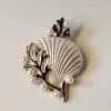 Entdecken Sie die Meeresschönheit in Form einer trendigen Brosche! Stell dir eine elegante Muschel mit goldglänzenden Rändern vor, geschmückt mit einem tiefblauen Algenmuster und kleinen perlenartigen Verzierungen. Sie fängt die Eleganz des Ozeans perfekt ein und verleiht Ihrem Outfit das gewisse Etwas. Lass dich von dieser stilvollen Kreation verzaubern und bring maritimen Glamour in deinen Look!.