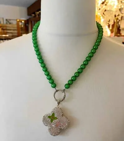 Entdecke das Zauberhafte: die magische Perlen-Halskette! 🌿✨ Schmiege dich im eleganten Style mit runden, grünen Perlen an und lass dich vom kleeblattförmigen Anhänger verzaubern, der mit funkelnden klaren Edelsteinen besetzt ist. Der zentrale grüne Stein setzt dem Ganzen die Krone auf. Trag das Glück am Hals und zieh alle Blicke auf dich! 💚🌟.