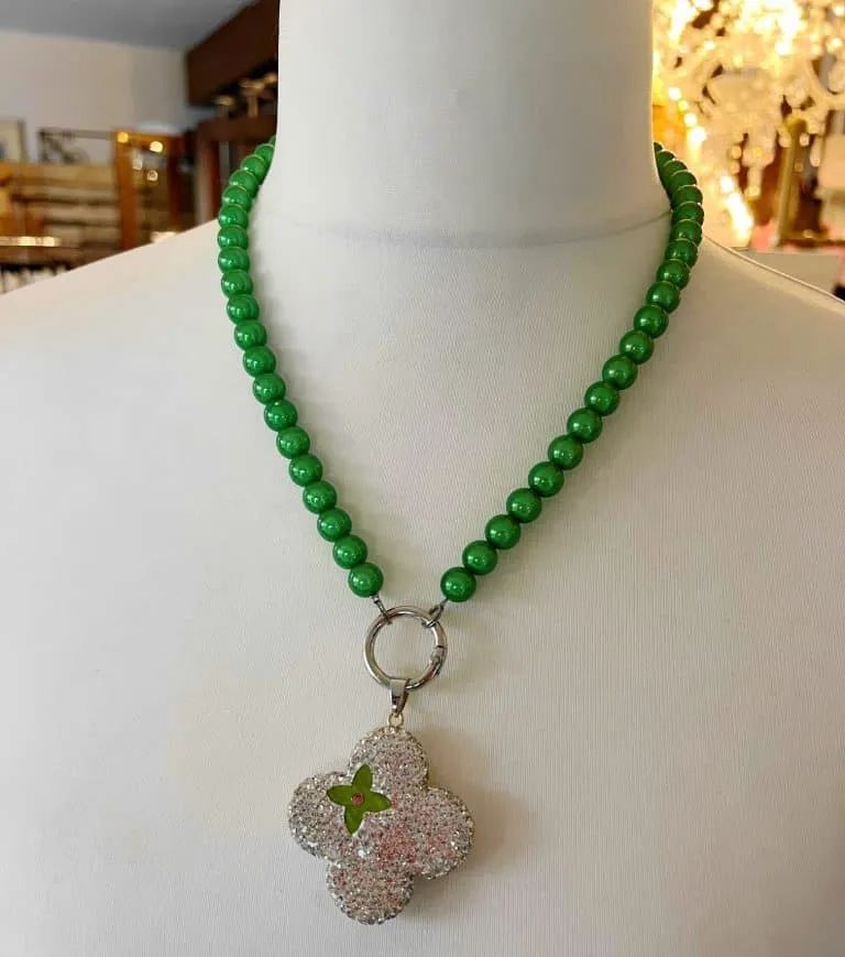 Entdecke das Zauberhafte: die magische Perlen-Halskette! 🌿✨ Schmiege dich im eleganten Style mit runden, grünen Perlen an und lass dich vom kleeblattförmigen Anhänger verzaubern, der mit funkelnden klaren Edelsteinen besetzt ist. Der zentrale grüne Stein setzt dem Ganzen die Krone auf. Trag das Glück am Hals und zieh alle Blicke auf dich! 💚🌟.
