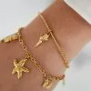 Entdecke Deine neuen Lieblings-Accessoires! Stell Dir vor, Dein Unterarm funkelt mit zwei Seestern Flex Goldarmbändern – eines verziert mit einem Seestern und Muschel, das andere mit einer eleganten Schnecke. Die dezente Ärmel im rechten oberen Blickfeld runden Deinen Look perfekt ab. Hol dir dieses Küsten-Feeling direkt an deinen Arm!.