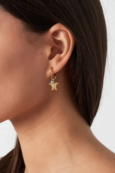 Entdecken Sie den coolen Glanz der „Turtle“-Ohrringe! Stell dir vor: Ein eleganter Close-up zeigt dich mit deinen langen, dunklen Haaren, während unser einzigartiger „Turtle“-Goldohrring im Rampenlicht steht. Der Ohrring ist mit funkelnden kleinen grünen Steinen verziert und baumelt stilvoll an einem schicken Hoop. Bringen Sie Tropenvibes in Ihren Look und sei der Hingucker auf jeder Party!.