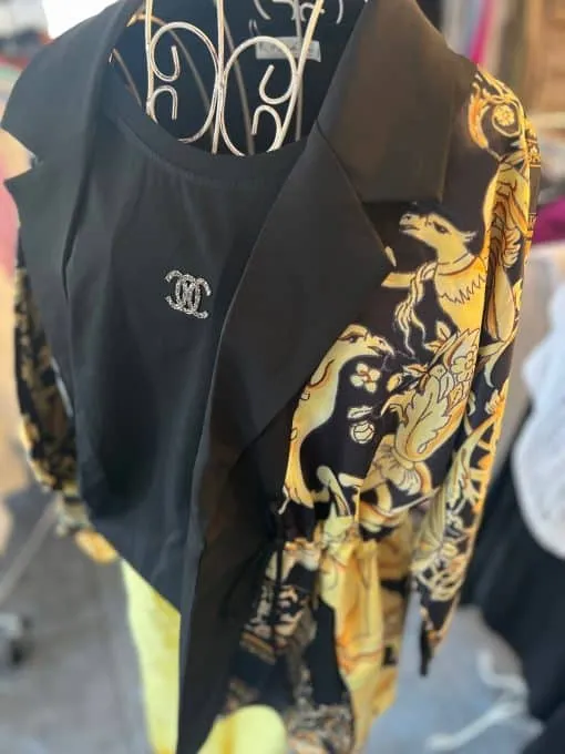 Entdecke den ultimativen Style-Kick mit diesem schwarzen Blazer! Auf dem Bügel präsentiert er sich mit einem raffinierten Muster aus gelben und goldenen Vögeln sowie stilvollen Blattmotiven, die sich elegant über die linke Seite erstrecken. Ein kleines, gesticktes Logo auf der linken Brust rundet deinen modernen Look ab. Hol dir dieses Fashion-Statement und stiehl allen die Show!.