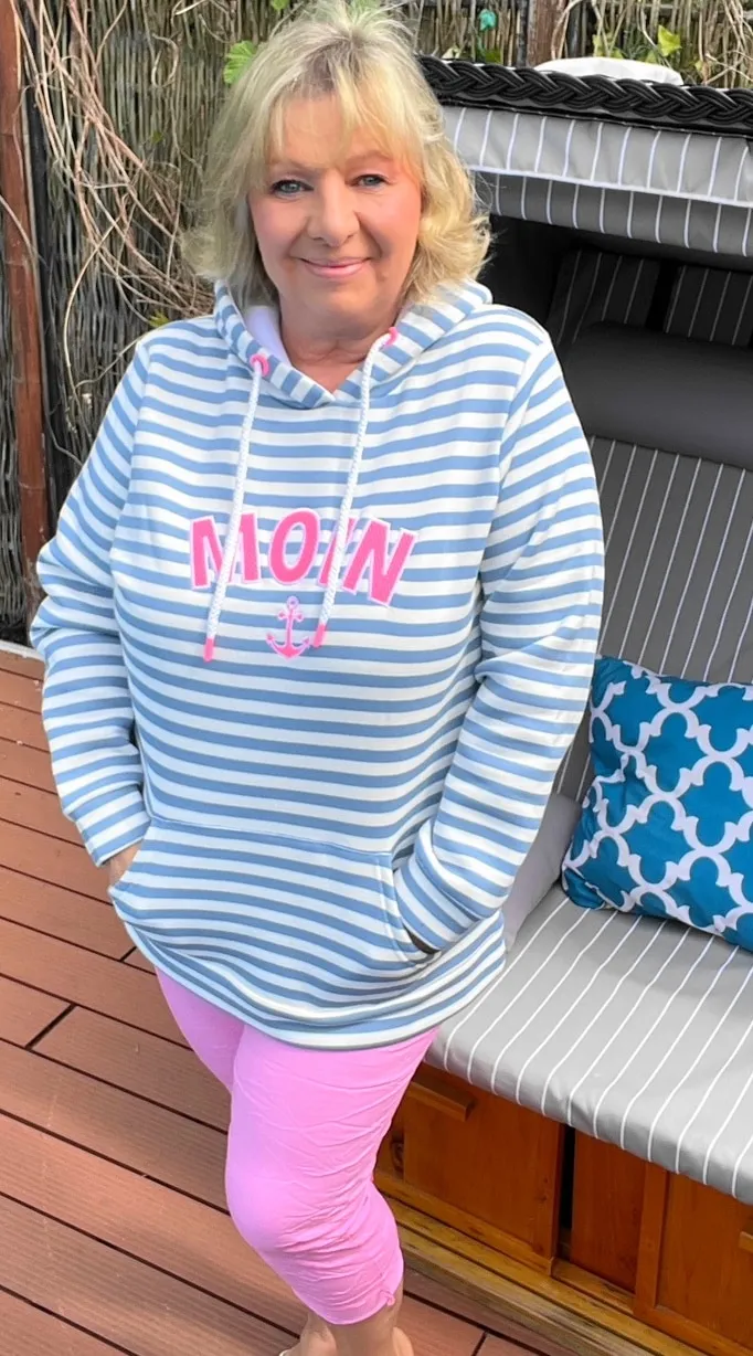 Stell dir vor: Du genießt einen entspannten Tag auf deiner Terrasse, die Sonne kitzelt dein Gesicht – und du strahlst im Zwillingsherz Damen Hoodie „MOIN“. Die hellblauen und weißen Streifen sind ein echter Hingucker, dazu die leichte Kapuze und das superweiche Material. Kombiniert mit einer coolen Hose in Pastellrosa setzt du stylische Akzente und versprühst gute Laune. Lehn dich zurück, Schnaps dir deinen Lieblingsdrink – mit diesem Look bringst du Frische und nordischen Charme in jede Auszeit!.
