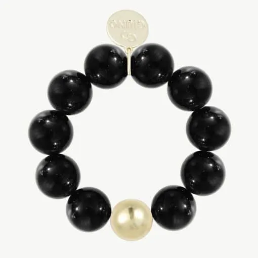 Trage das GIUNO Bold Beads Armband und setze ein starkes Statement! Die markanten schwarzen Perlen kombiniert mit einer einzelnen goldenen Perle verleihen deinem Look zeitlose Eleganz. Das stilvolle, dezent glänzende 