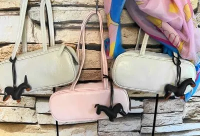 Entdecke deinen neuen Lieblingslook: Drei elegante Handtaschen - zwei in klassischem Weiß, eine in trendigem Rosa - bringen frischen Wind in dein Outfit. Das Highlight: Verspielte Dackel-Anhänger verleihen jeder Tasche einen modernen Twist. Lass dich inspirieren und setze auf stylische Accessoires, die garantiert alle Blicke auf sich ziehen!.