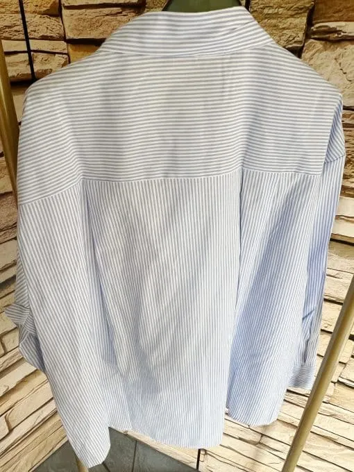 Erlebe die Seaside Bluse: Zeitloses Streifendesign in Hellblau und Weiß, perfekt präsentiert vor stilvoller Steinoptik - für deinen Look!.