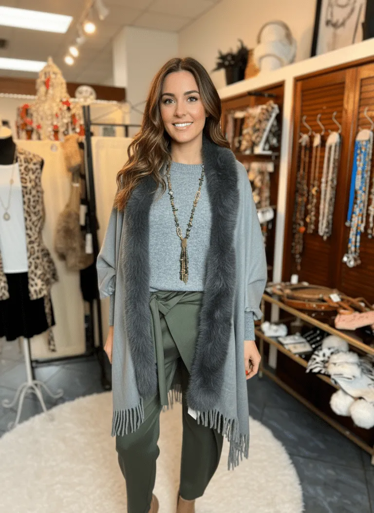 Erlebe deinen Style: Im grauen Jolina Poncho Schal, grüner Hose und Statementkette strahlst du zwischen trendigen Accessoires.