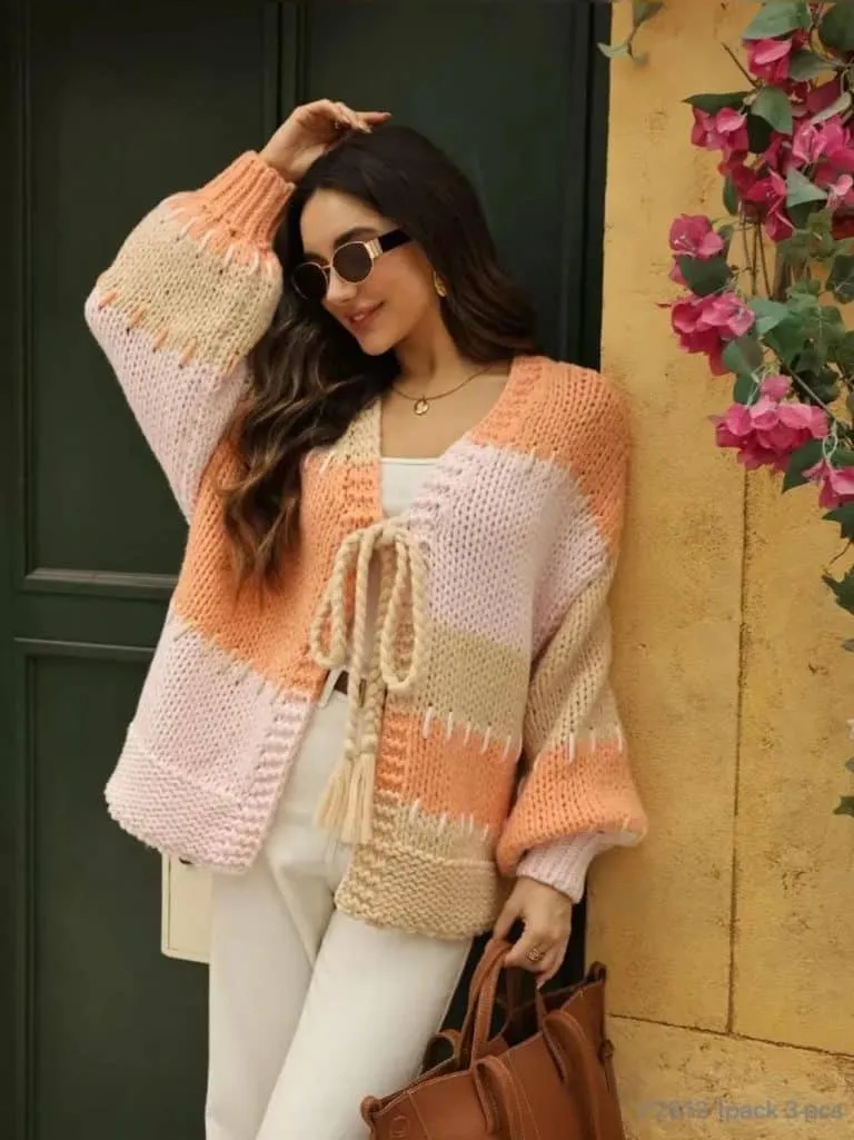 Du trägst stylische Sonnenbrillen, einen modernen Strickcardigan in Pfirsich-Beige und deine Trend-Bag vor der grünen Tür.