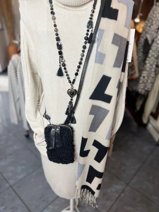 Tragen Sie das cremefarbene Rollkragenkleid mit schwarzer Statementkette, modernem Schal und der stylischen Handy Teddy Tasche.