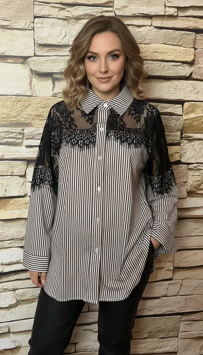 Du strahlst Selbstbewusstsein aus, trägst ein modernes Streifenshirt mit Spitzenakzenten vor urbaner Steinwand und lächelst charmant.