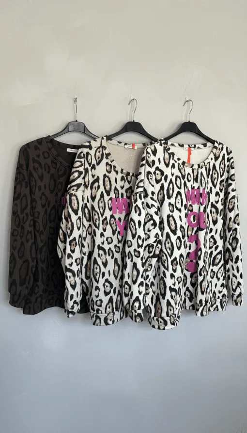 Entdecke deinen neuen Style: ARE YOU OK Sweatshirts im Leo-Look mit pinker Schrift, stylisch auf schwarzen Bügeln präsentiert.