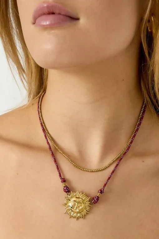 Trage du den trendigen Layer-Look mit goldenen Ketten und setze ein Statement mit dem Sun Kette Anhänger am roten Band.