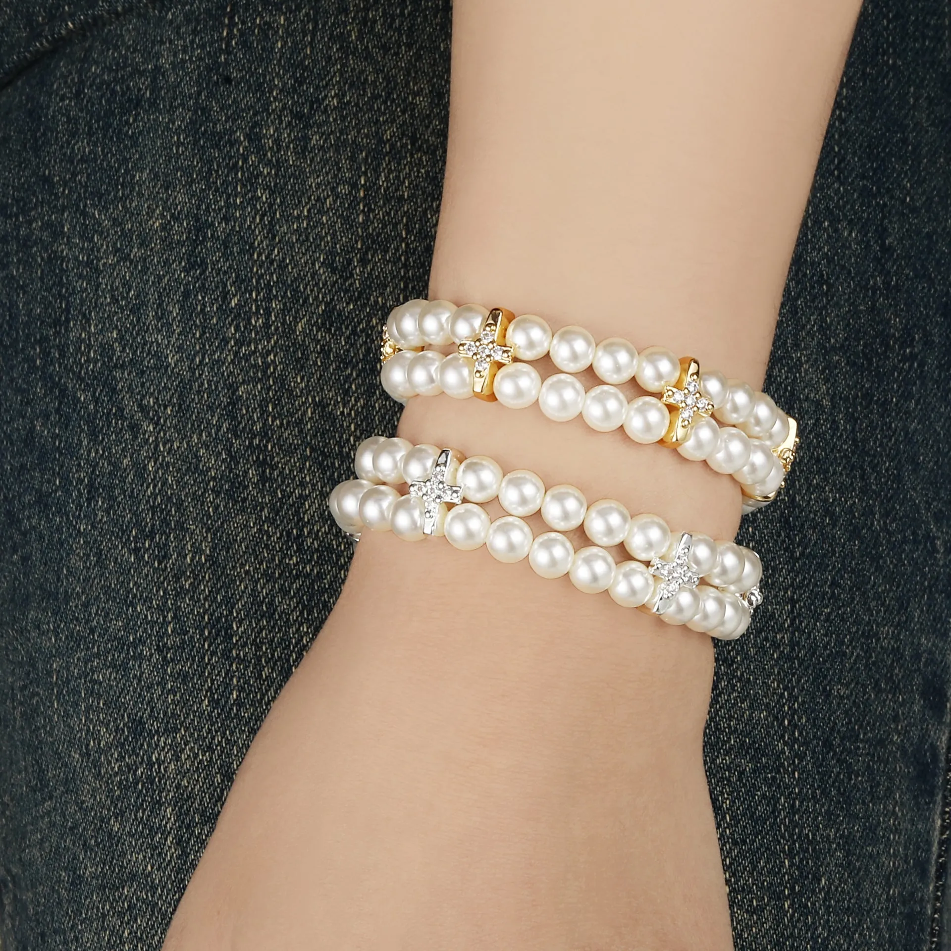 Trage zwei stilvolle Perlenarmbänder - darunter das glamouröse Golden Cross mit funkelnden Kristallen - elegant zu Denim!.