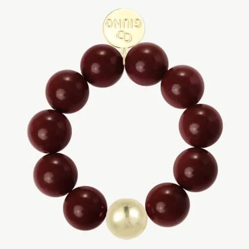 Erlebe das GIUNO-Armband: Kraftvolle bordeauxrote Perlen, ein goldener Akzent und gravierte Scheibe für deinen Signature-Look.