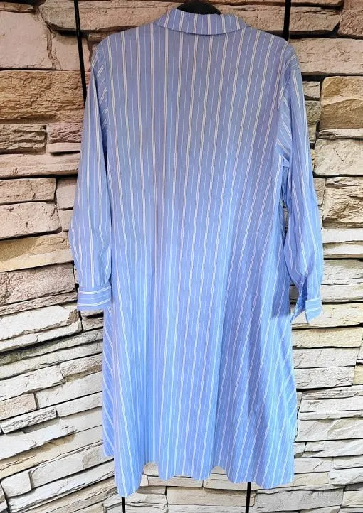 Entdecke das Lindsay Paris Patch Blusenkleid mit langen Ärmeln und blauen Streifen - dein moderner Look vor rustikaler Steinwand.