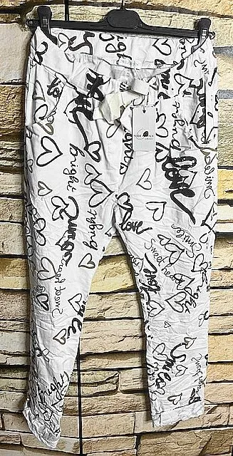 Entdecke deine neue Lieblingspants: Weiße Hose mit angesagten schwarzen Wörtern und Herzdoodles, stylisch am Haken inszeniert.