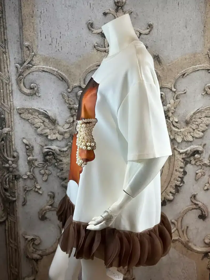 Perl Vision Sweatshirt: Weißes Sweatshirt mit braunen Rüschen und Perlen auf einer Schaufensterpuppe.