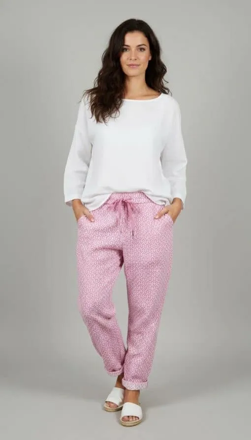 Erlebe den Zauber: Du strahlst in weißem Longsleeve und der zauberhaften Relax Hose mit pinken Mustern vor grauem Hintergrund.