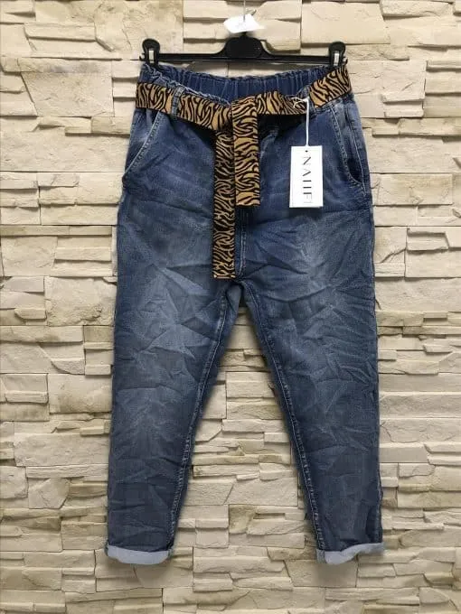 Entdecke deinen Style: Trendige Blue Jeans mit coolen Umschlägen und Animal-Print-Gürtel, perfekt präsentiert vor Steinwand.