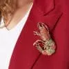 Verleihe deinem Look ein Statement: Die Turf-Anstecknadel setzt an deinem roten Blazerlapel funkelnd-elegante Akzente.