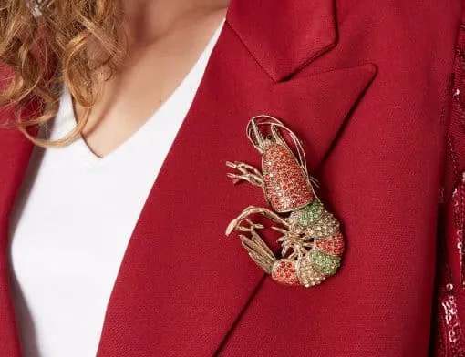 Verleihe deinem Look ein Statement: Die Turf-Anstecknadel setzt an deinem roten Blazerlapel funkelnd-elegante Akzente.