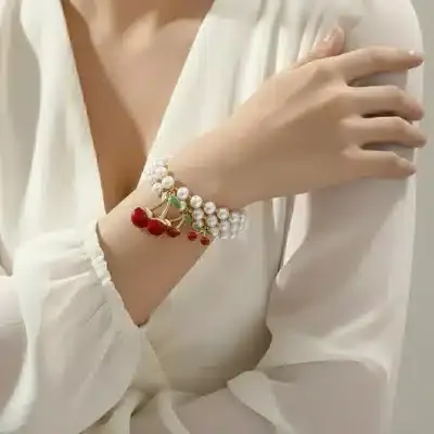 Setzen Sie ein Statement: Trage das Cherry Pearl Armband mit verspielten roten Kirsch-Charms zu deiner weißen Bluse und strahle Modernität aus.