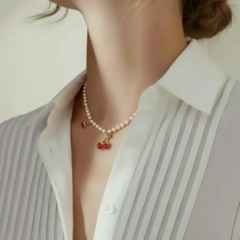 Trage die Cherry Pearl Kette zu deiner weißen Bluse und setze mit stilvollen Perlen und verspielten Kirsch-Anhängern ein Statement.