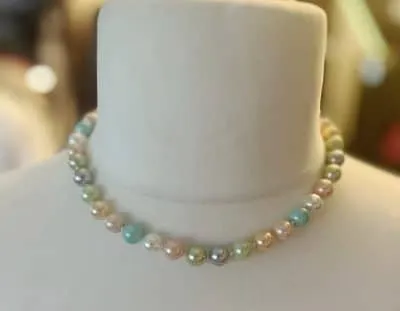 Entdecke deine neue Lieblingskette: Sanfte Pastelltöne schimmern auf edlen Perlen, stilvoll präsentiert am weißen Busen.