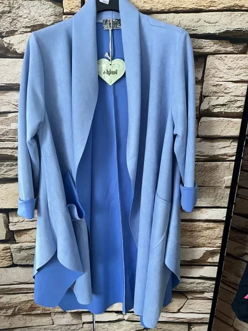 Erlebe den modernen Look: Dein hellblauer Cardigan mit lässig gerollten Ärmeln vor stylischer Steinwand wartet auf dich!.