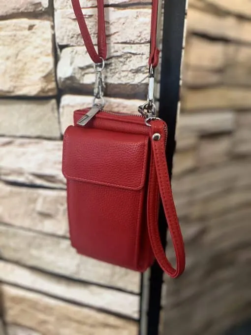 Entdecke deine neue Lieblings-Bag: Die kleine rote Ledertasche mit Handgelenkschlaufe setzt moderne Akzente vor urbaner Steinwand.