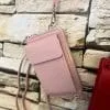 Entdecke deine neue Lieblingsbegleiterin: Die stylische pinke Crossbody-Tasche mit praktischem Handgelenkriemen vor Steinwand.
