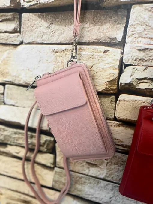 Entdecke deine neue Lieblingsbegleiterin: Die stylische pinke Crossbody-Tasche mit praktischem Handgelenkriemen vor Steinwand.