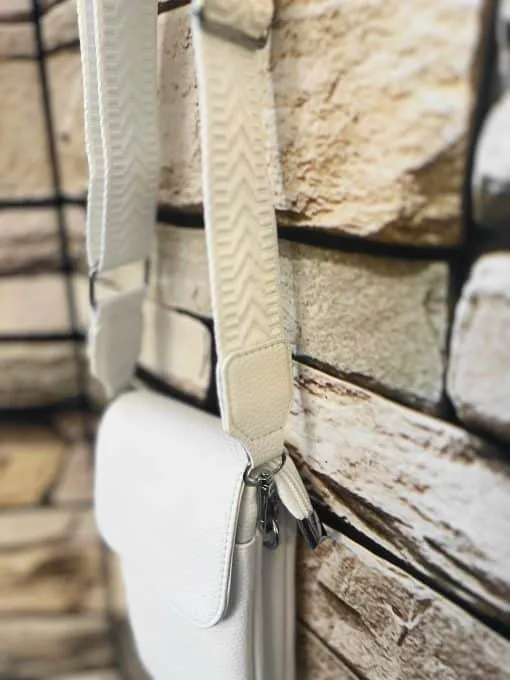 Tragen Sie diese weiße, strukturierte Shoulder Bag mit breitem Riemen und setzen Sie ein modernes Statement vor urbanem Steinmuster.