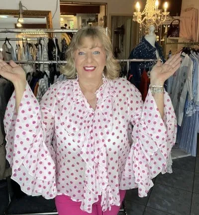 Entdecke deinen Look: Strahle in der Punkteprinzessin Bluse, hebe die Arme und genieße Modevielfalt im bunten Boutique-Ambiente.