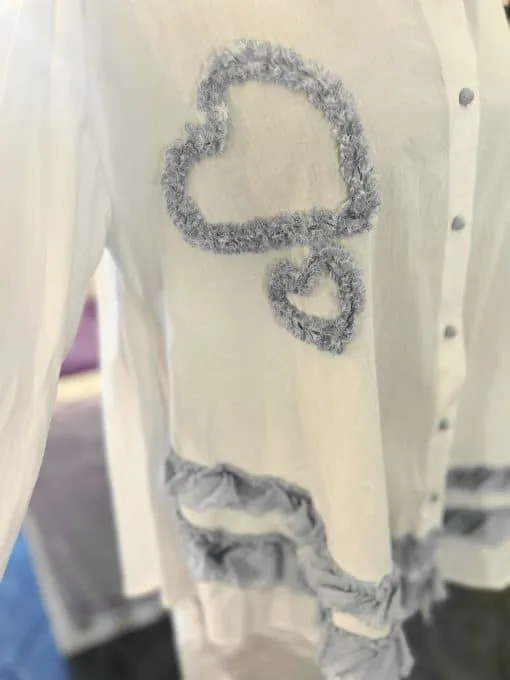 Zieh dir dieses weiße Shirt mit flauschigen blauen Herzen an und kreiere trendige Denim-Looks mit verspieltem Layering!.