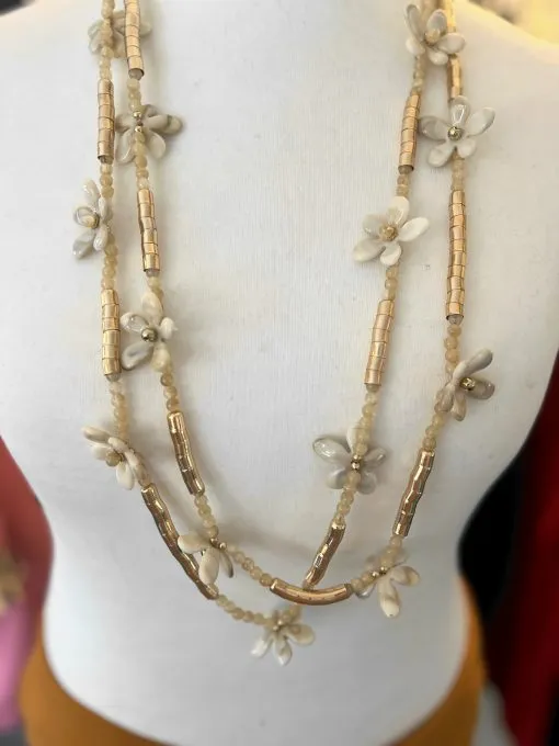 Entdecke deine elegante Seite mit der Blütenzauber Halskette - cremefarbene Blüten und goldene Perlen glänzen an deinem Hals.