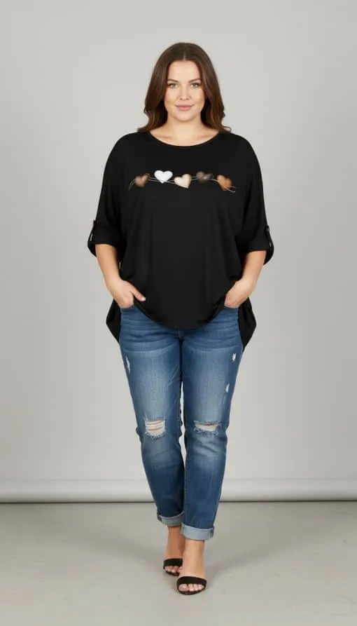 Setze ein Statement: Du trägst ein schwarzes Top mit Herzchen, coole blaue Ripped Jeans und stylishe Sandalen vor grauem Hintergrund.