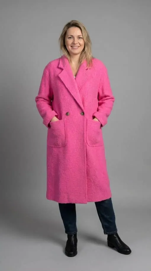 Du strahlst mit einem Lächeln, trägst den Cozy Long Mantel in Pink zu Jeans und schwarzen Boots - lässig und stylish zugleich.