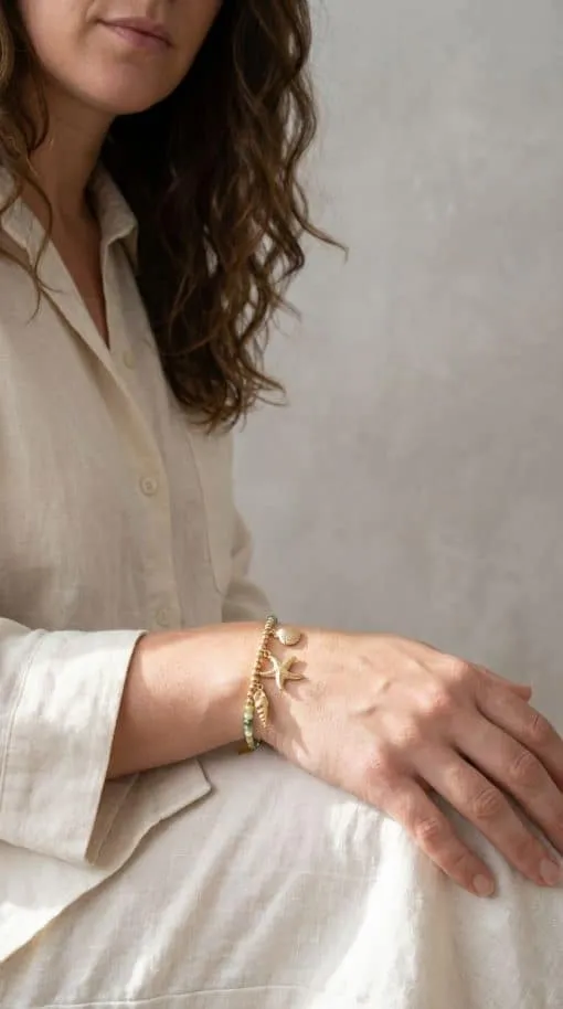 Du sitzt stilvoll im beigen Kleid, trägst das Shell-Love Armband und setzt so ein modernes Statement für Eleganz und Trendgefühl.