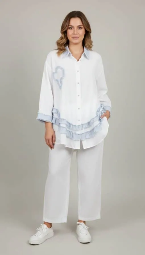 Du setzt ein modernes Statement: Lässiges weißes Outfit mit blauen Akzenten und Sneakern vor cleanem, hellem Hintergrund.