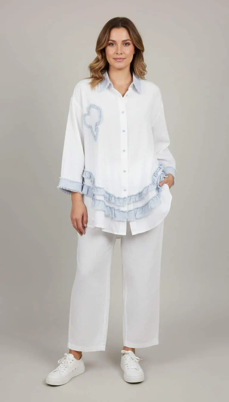 Du setzt ein modernes Statement: Lässiges weißes Outfit mit blauen Akzenten und Sneakern vor cleanem, hellem Hintergrund.