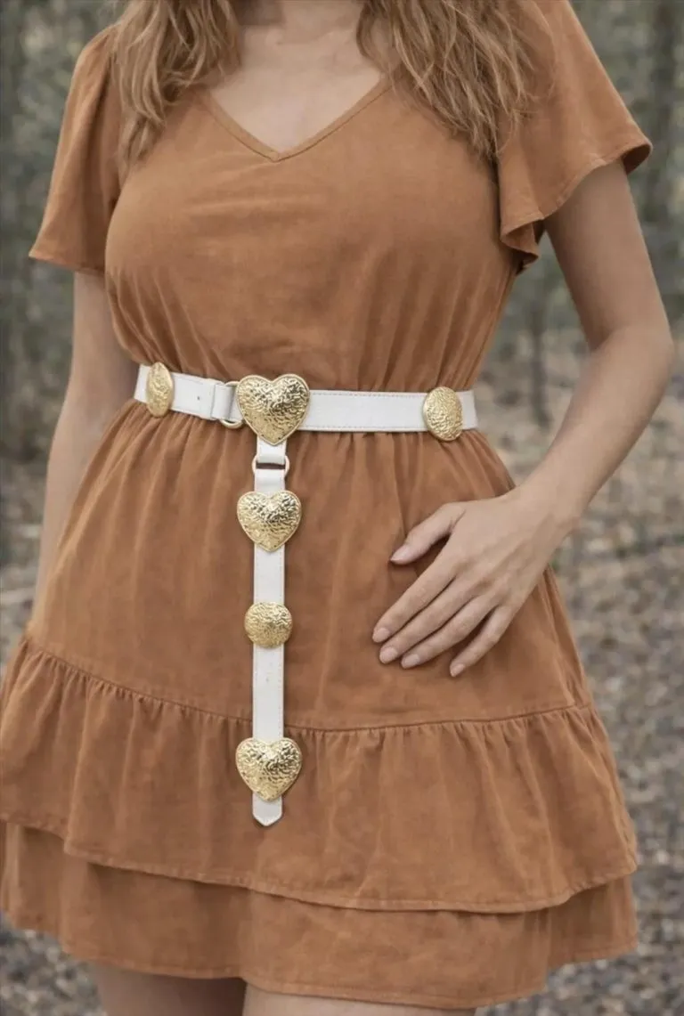 Amor Gürtel: Weißer Herzgürtel zu braunem Kleid. Modeaccessoire mit goldenen Herzdetails.