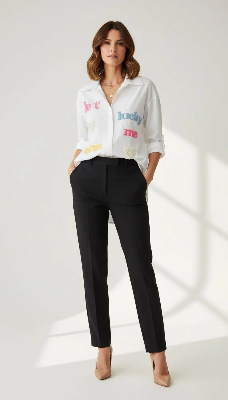 Lucky Me Hemdbluse: Frau in weißer Bluse mit Aufdruck und schwarzer Hose. Modische Damenbekleidung.