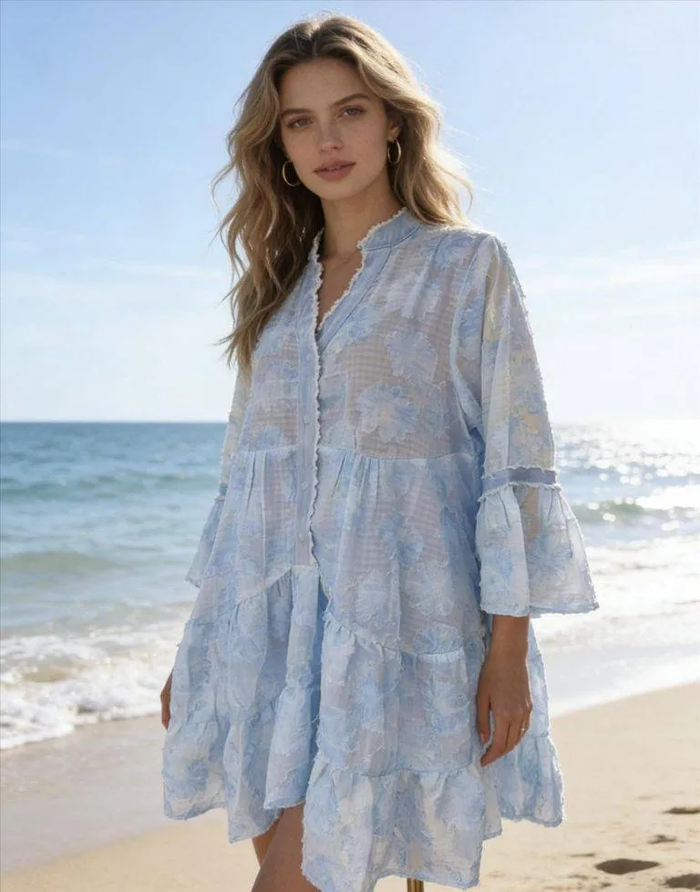 Ocean Breeze Tunikakleid: Blonde Frau am Strand mit blauem Boho-Kleid. Sommerliche Strandmode.